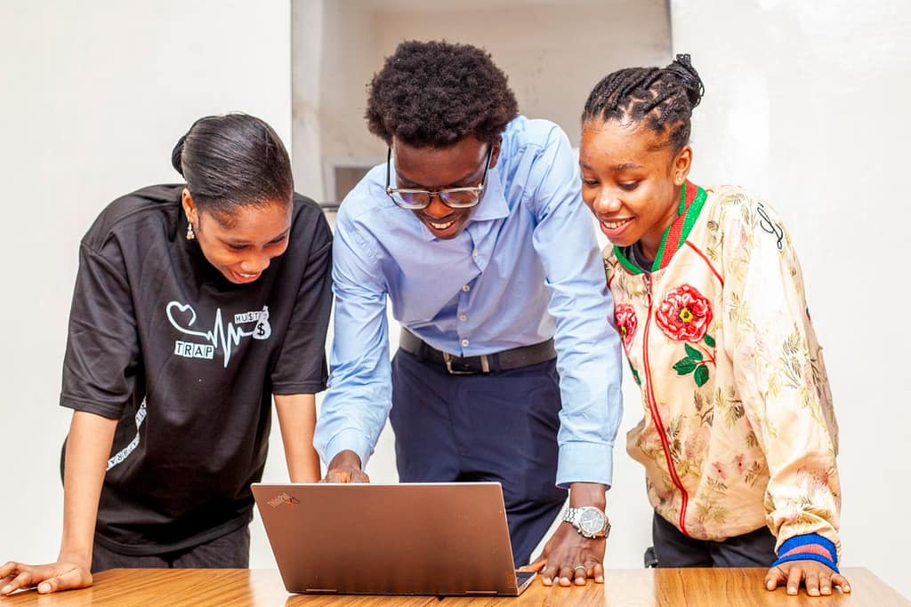 Three young student looking at a laptop technology