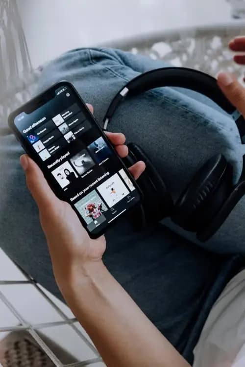 Phone screen with spotify open and headphones